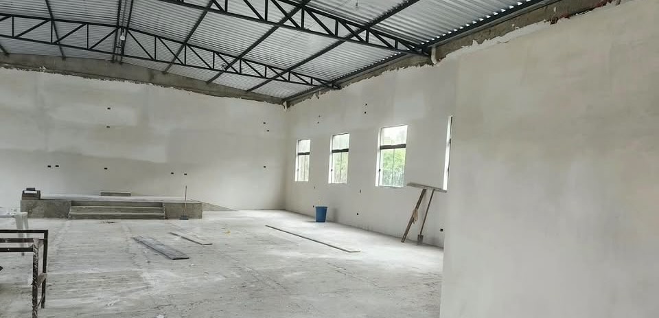 Parede lateral direita do salão com janelas e ferramentas de limpeza